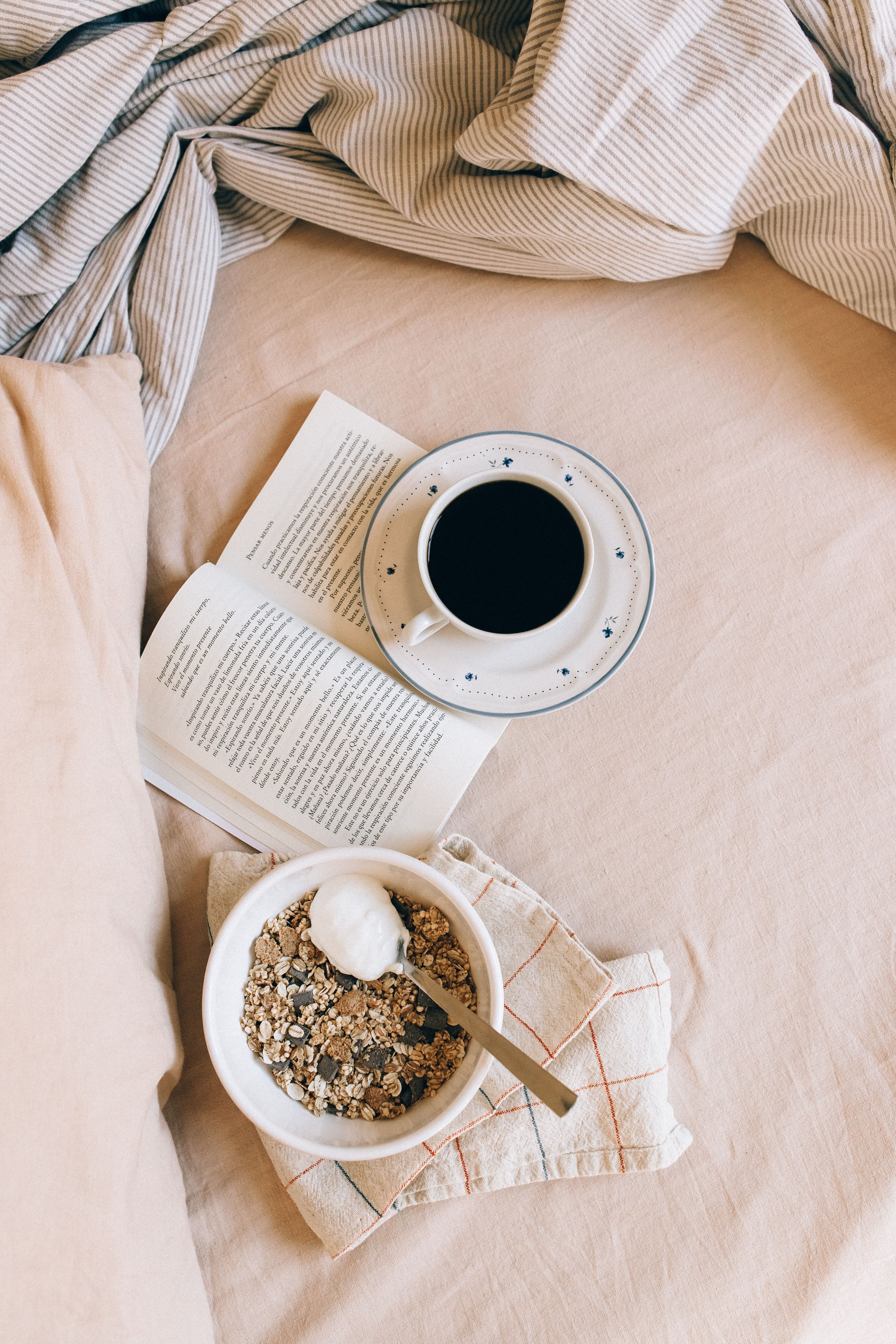 book, coffee, and granola on linen sheets